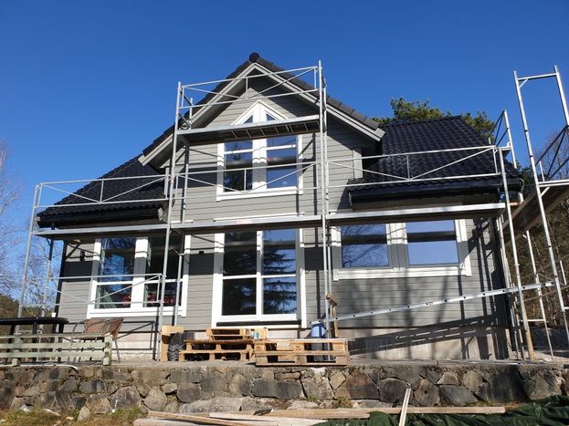 Grått toetasjes hus med stillaser