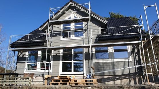 Grått toetasjes hus med stillaser